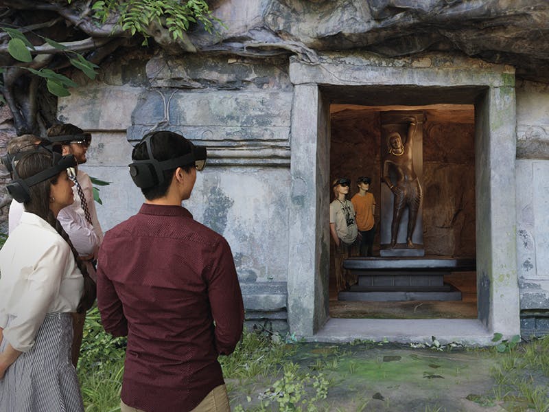 a group of people wearing HoloLens headsets look at a digital rendering of a cave